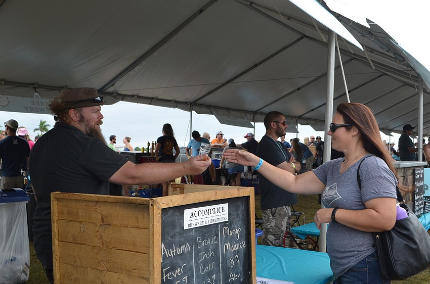 Matt Stetson of Accomplice Brewery and Ciderworks hands Jessica Sullivan a sample during Sip the Sunshine.