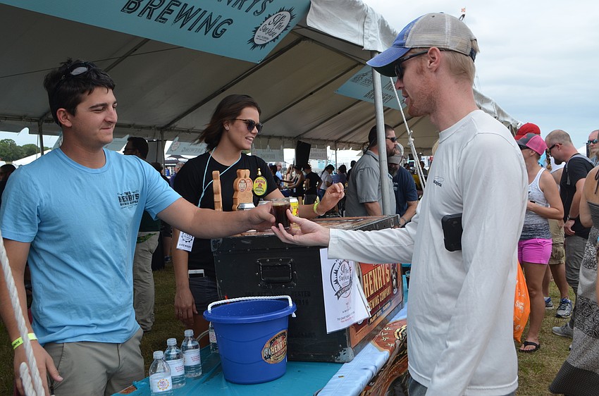 Vince Oriti of Two Henry’s Brewing hands Ryan McCarthy a sample during Sip the Sunshine.