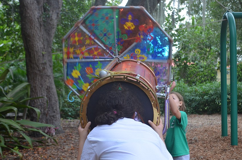 Angel Thomas peaks through a large kaleidoscope while Savannah McEachern turns the color wheel during the Tunes in the Park neighborhood potluck on Saturday night in Laurel Park.