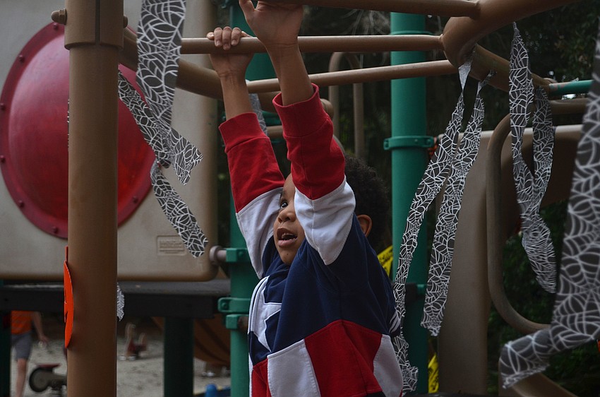 Jiraiya Boulton, 6, plays on the monkey bars during the Tunes in the Park event on Saturday evening in Laurel Park.