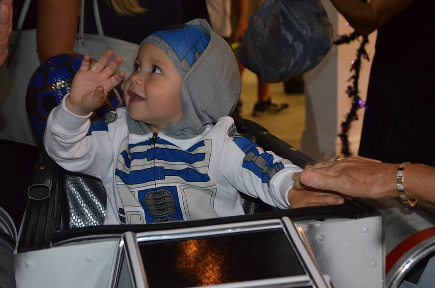 Hunter Rankin, 2, waves to the crowd. Rankin was dressed as R2D2. His dad, who dressed as Darth Vader, built the X-Wing Starfighter for the occasion.