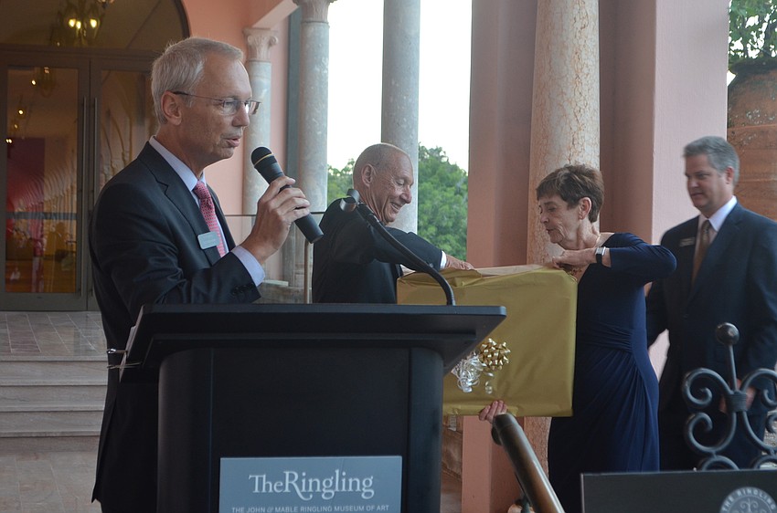 Executive Director of the Ringling Steven High thanks Keith and Linda Monda as the couple opens their present of a portrait of “Pathless Woods” exhibit artist Anne Patterson.
