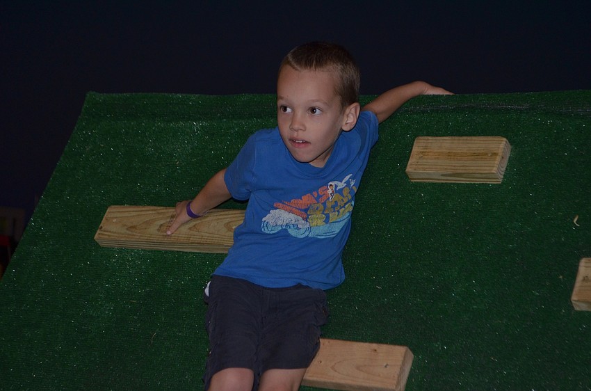 Lakewood Ranch 5-year-old Roman Obukhov climbs down a wall of the obstacle course.