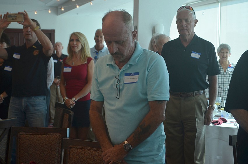 Joseph Dromeshauser stands with his head bowed before attendees sang the Marine anthem to end the event.