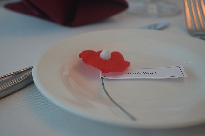 Red poppies, with a note expressing thanks decorated each of the place settings. The flowers, which were the first the flower on Flanders fields after World War I, are a symbol of remembrance for military veterans.