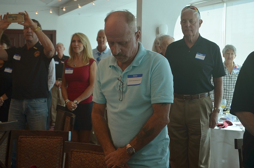 Joseph Dromeshauser stands with his head bowed before attendees sang the Marine anthem to end the event.