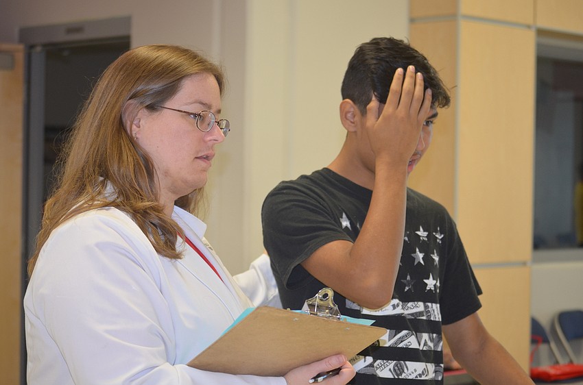 Volunteer Jessica Ragan, an optometry student, leads Bradenton 14-year-old Jorge Manzanares  through an eye exam.