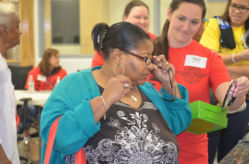 Bradenton's Zanthia Monroe tries on glasses with help from Sarasota volunteer Jenny King.