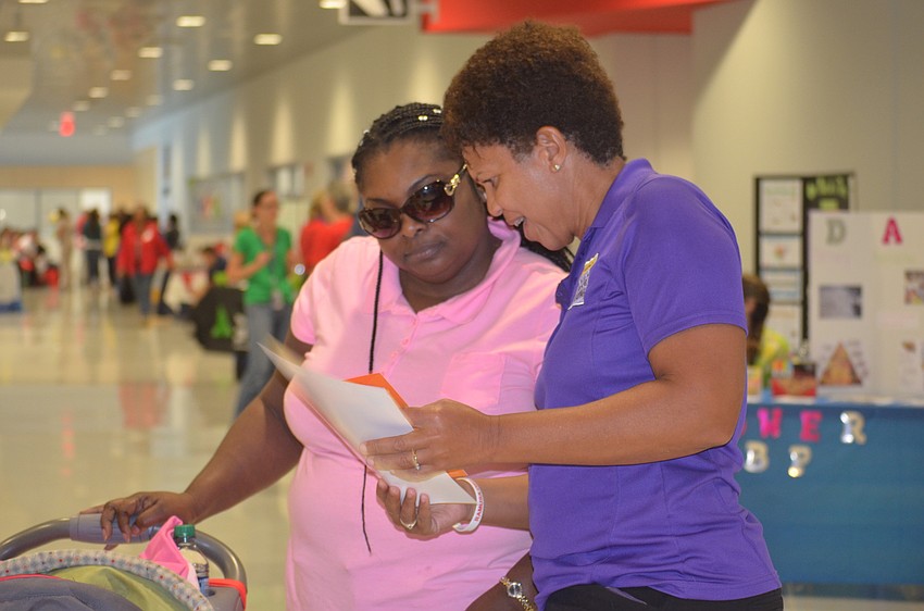 Kelly Karen, a volunteer with Suncoast Campaign for Grade Level Reading, shows Sarasota's Paula Rolle some books.