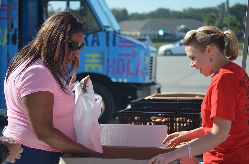 Chantal Lovell, a volunteer at the Remote Area Medical free clinic, helps Bradenton's Letisha Calloway pick out some free vegetables.