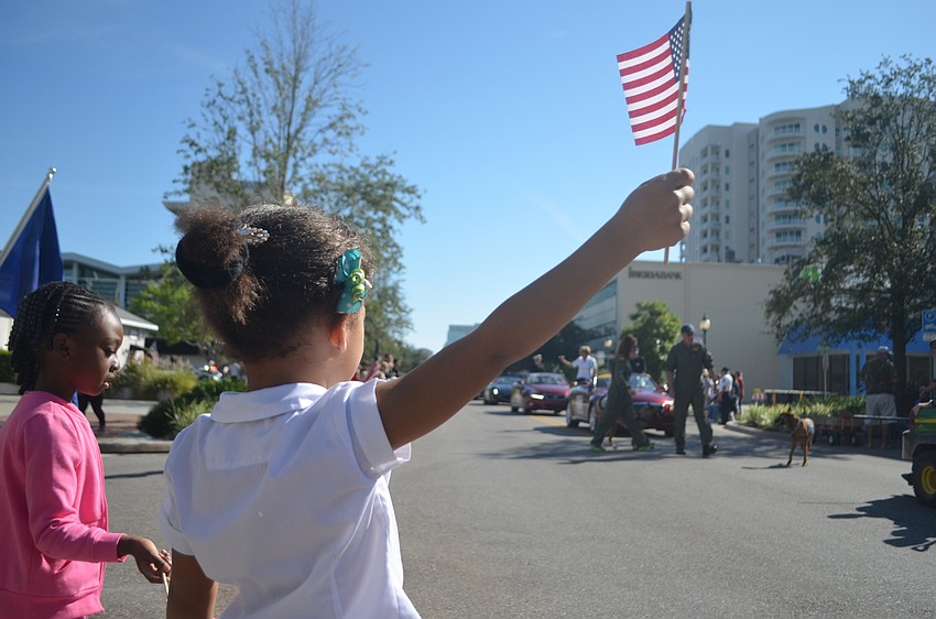 Jaliyah Campbell waves and American flag while watching the veteran's procession during the Veterans Day parade.