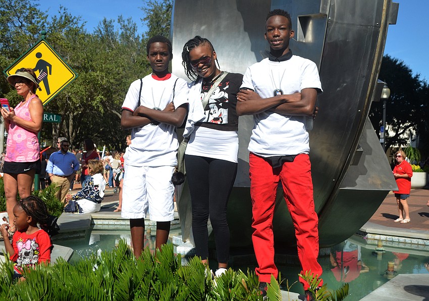 Zaire Gladden, Loretta Spann-Gladden and Nasir Gladden stand on the fountain near Five Points Park to watch the parade near the end of its route through downtown.