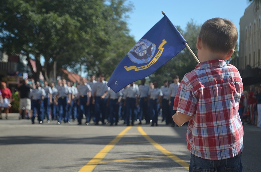 James Hembree waves a United States flag while watching Booker High School students march in the Veterans Day parade.