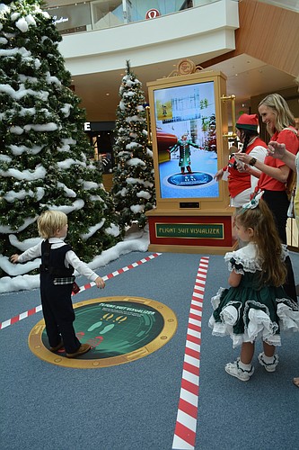 Palmetto's John Tucker, 3, tries on a virtual flight suit before visiting with Santa.