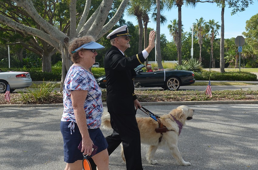 Ed Burton with his wife, Betty, and Southeastern Guide Dog, Sammy, waves to the crowd during the third annual Longboat Key Veterans Day Parade.