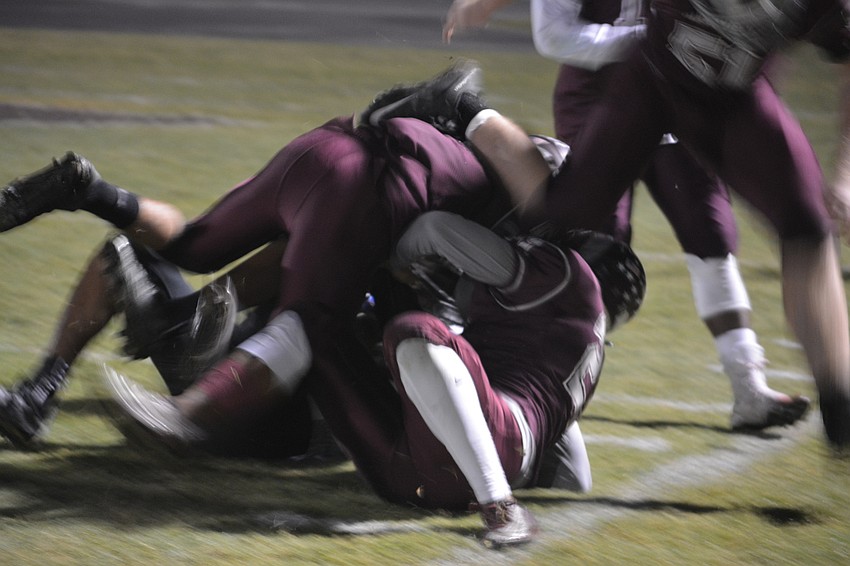 Two Riverview defenders swallow up an Olympia runner short of the goal line. The Rams beat the Titans 56-25.
