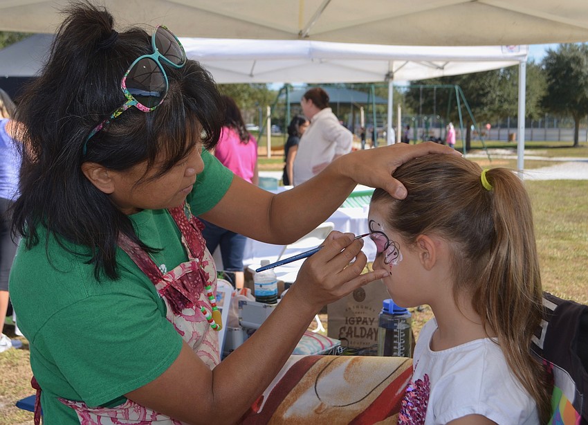 Akiko Campbell puts her artistic touch on the face of Riverwalk's Paige Broderick.