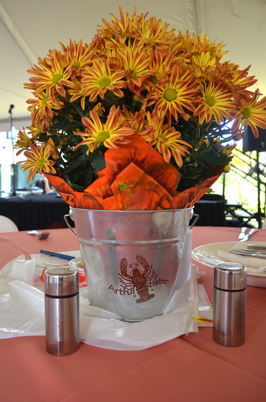 Floral centerpieces in themed buckets adorn each table.