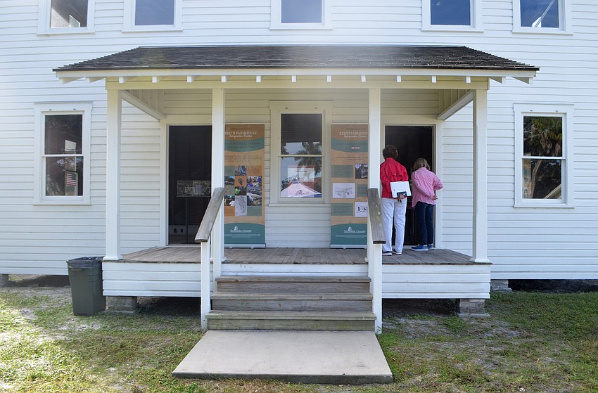 Friends of Sarasota County Parks board member Roxanne Williamson and Sarasota County Parks and Recreation Director Carolyn Brown peak inside the Phillippi  farm house. The first residence on the property, the structure is in the process of being restored.