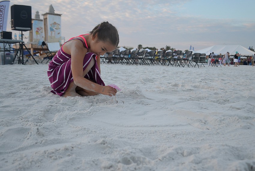 Kira Smith puts the finishing touches on her sand angel.