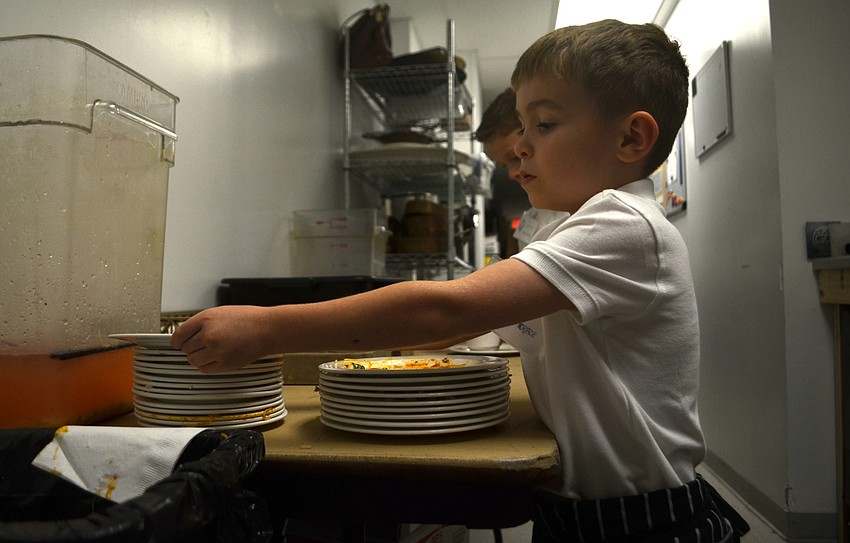Southside First-grader Leo Tondryk sorts dirty dishes in The Francis kitchen.