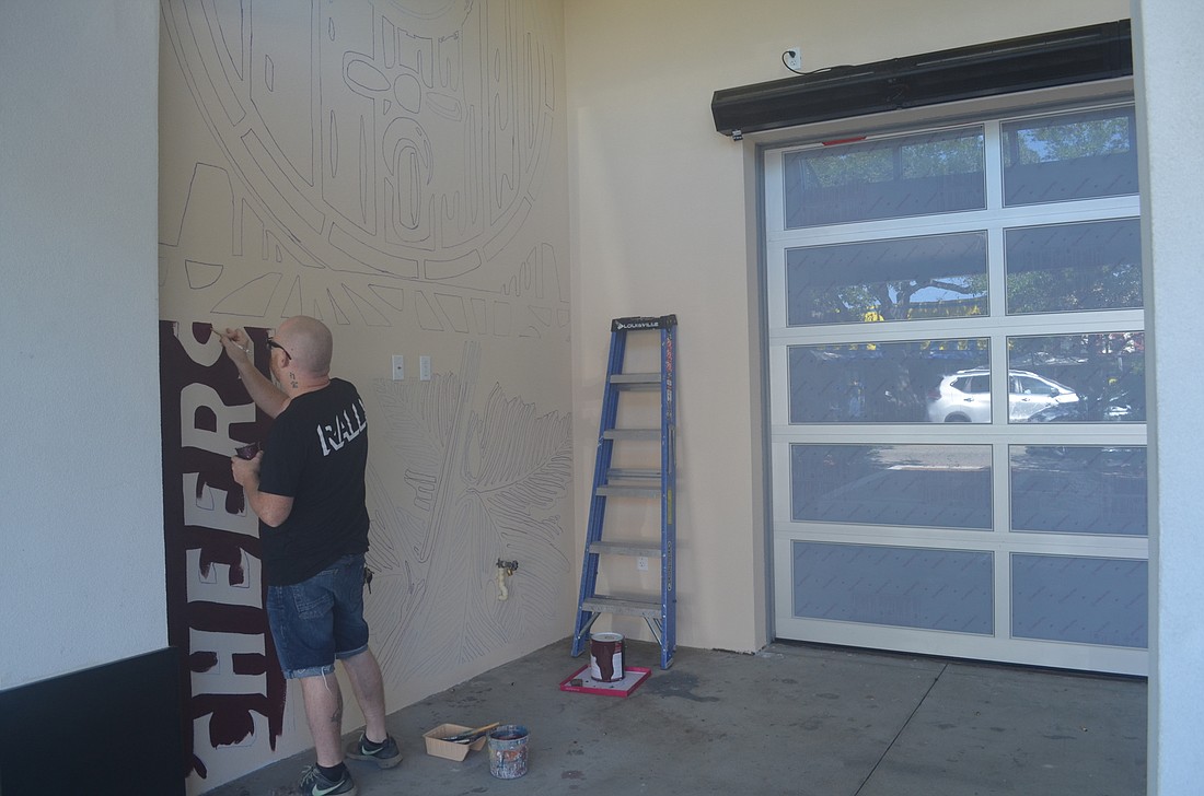 Josh Pearson paints a wall in front of the planned Cask and Ale on Main Street. Despite pending litigation, work continues on the bar and restaurant.