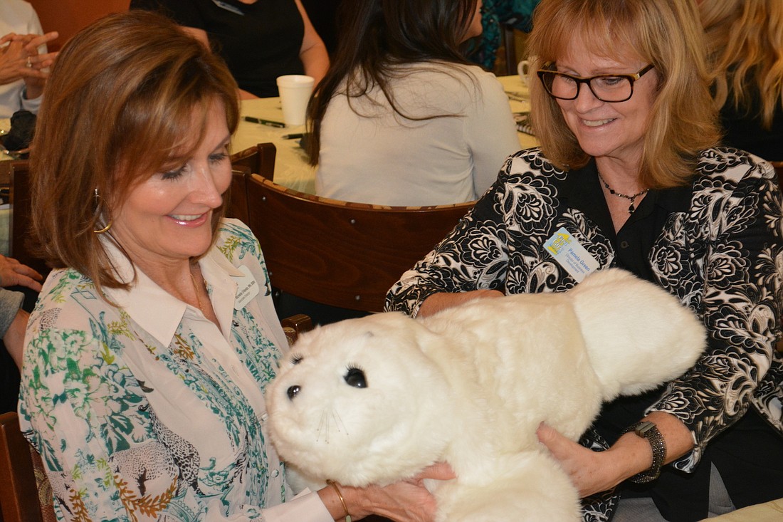 Michelle Orlando, the associate director of Bayada Home Health Care, tries out the robotic seal with Pamela Green, the director of business development for First in Care.