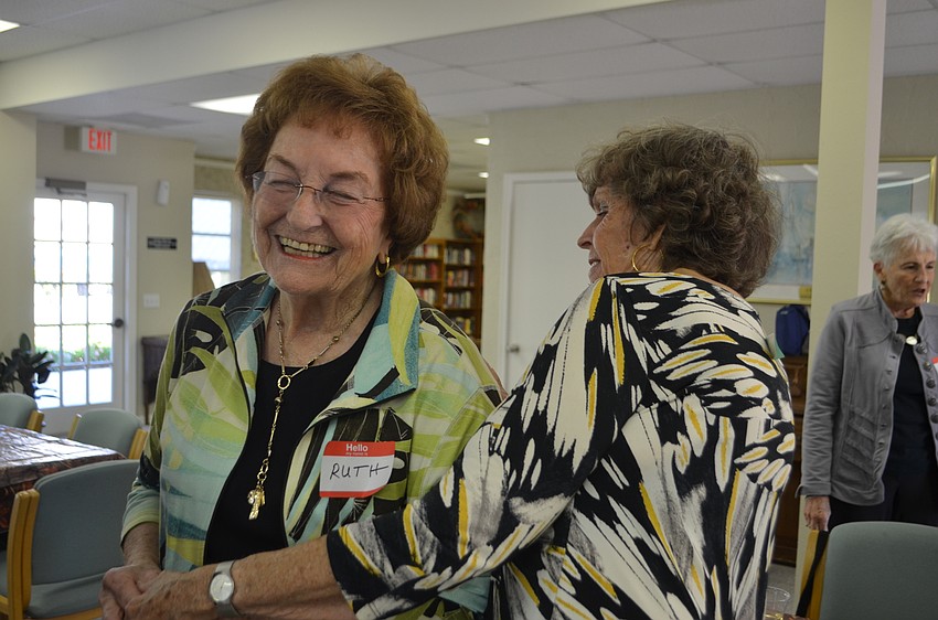 Ruth Strauss and Donna Godrey laugh as Godrey checks Strauss’ back for a sticker during an ice-breaker game.