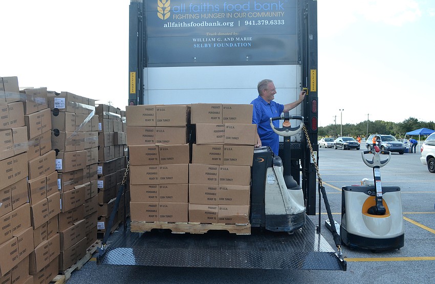 Food distribution coordinator Robbie Coats unloads frozen turkeys from a truck during the drive.