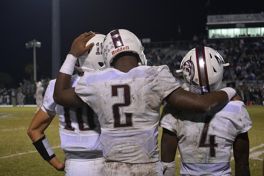 Braden River junior running back Deshaun Fenwick puts his arms around seniors Louis Colosimo and Raymond Thomas.