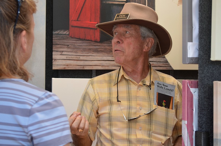 Don Plumridge discusses his paintings with festivalgoers.