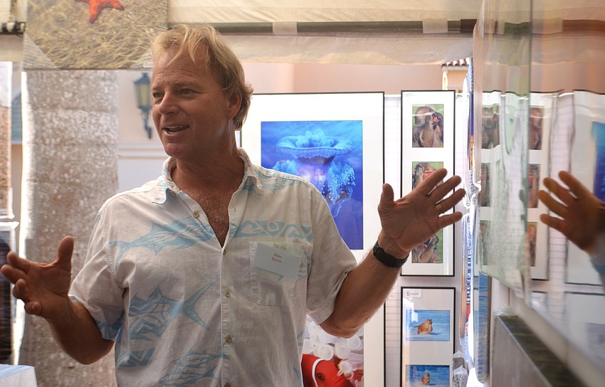 Marine photographer Mike Bacon discusses one of his favorite photos with visitors to his tent at the Sarasota Fall Fine Art Festival.