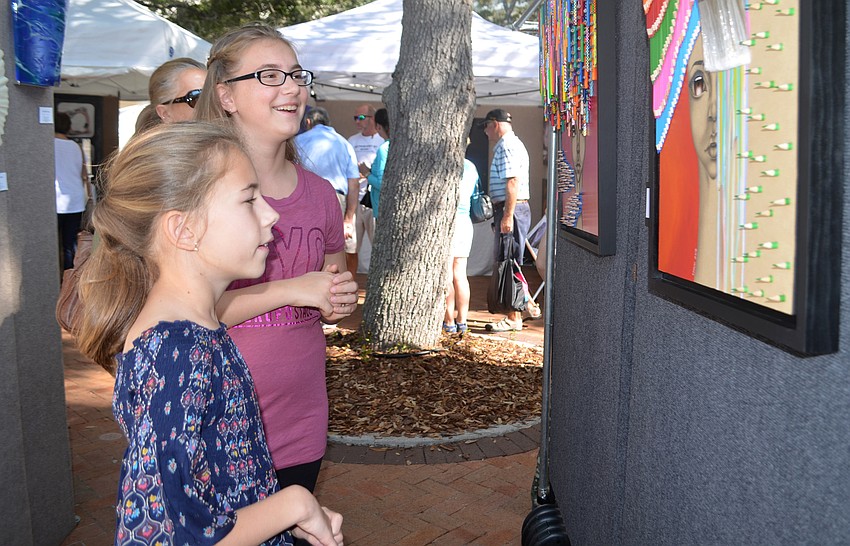 Maya Csutha and Abigail Pal admire one of the pieces featured at the Sarasota Fall Fine Art Festival.