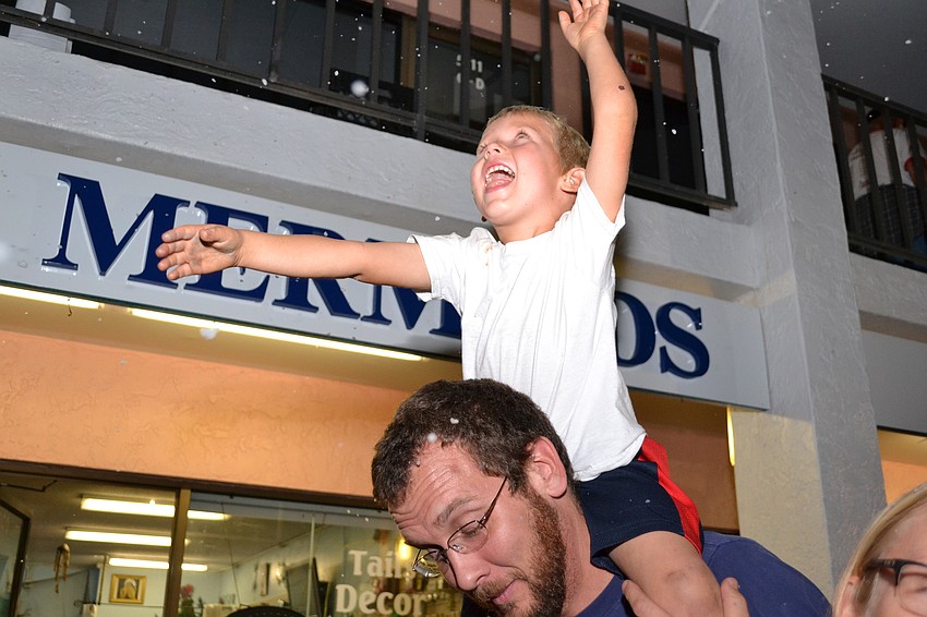 Dean Brady catches falling snow as he sits on his father Brandon Brady' s shoulders.