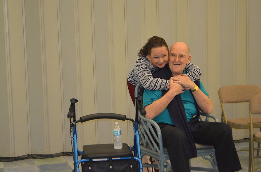 Michelle Giglio hugs monsignor Gerard Finegan after they sang together at St. Mary’s holiday party.