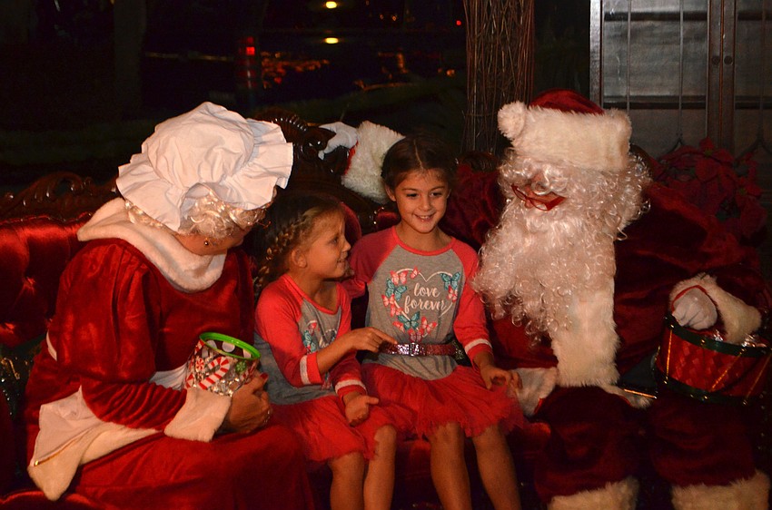 Teddy, 5, and Lennon Seguso, 6, talk with Mrs. Claus and Santa Claus.