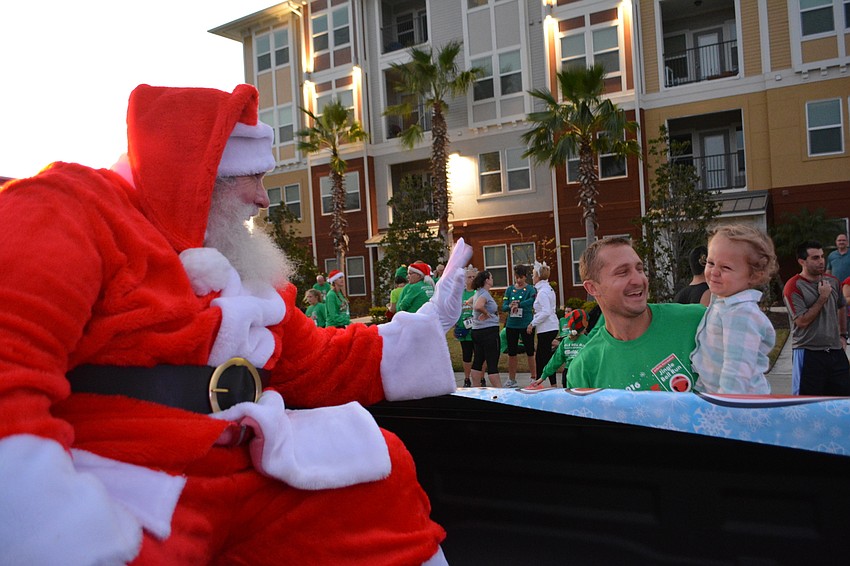 Santa (Bradenton' s Tom Jensvold) tries to get 2-year-old Evan Billingham of Lakewood Ranch to give him a high five, as Evan' s dad, Dr. Chris Dillingham, looks on.