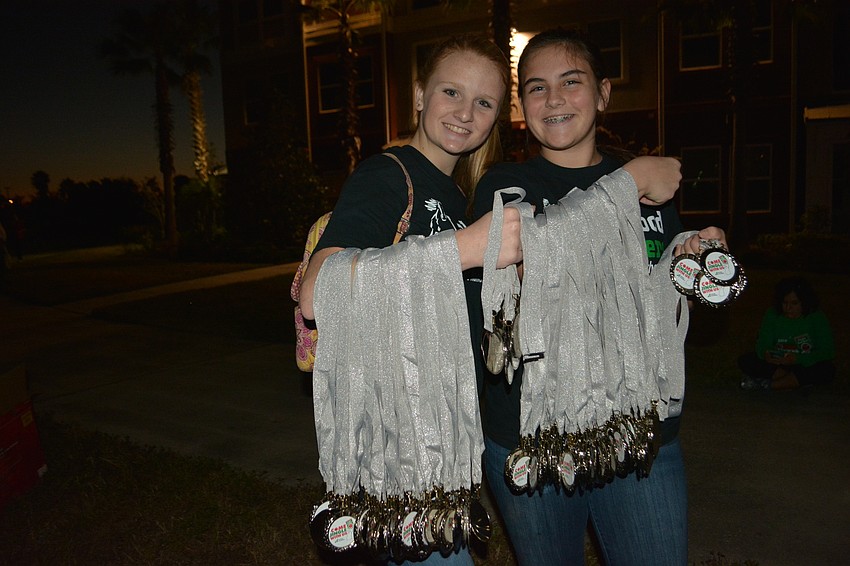 Morgan Hoffman and Jenna Schaefer were volunteers who handed the runners medals after the race.