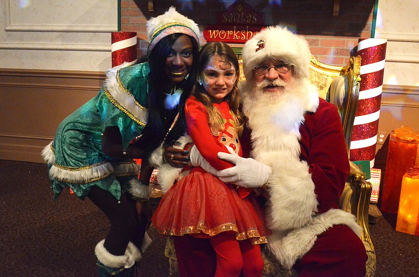 Alexandria Rains, 5, gets her photo taken with Santa Claus and one of his elves.