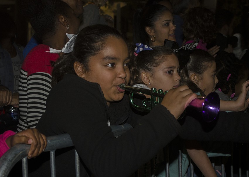 Reynalise Allen blows on her toy horn during the Holiday Parade Saturday evening in downtown Sarasota.