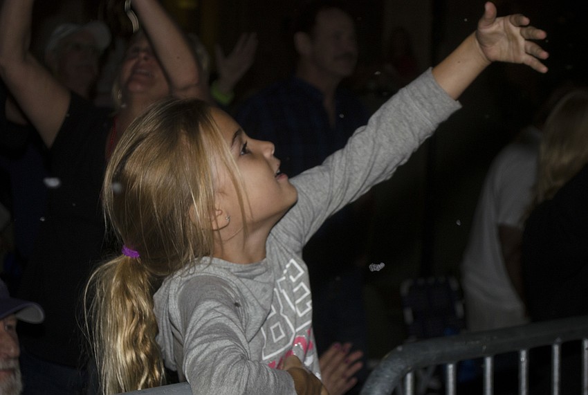 Catalina Coy tries to catch the fake snow blown at the crown during the parade.