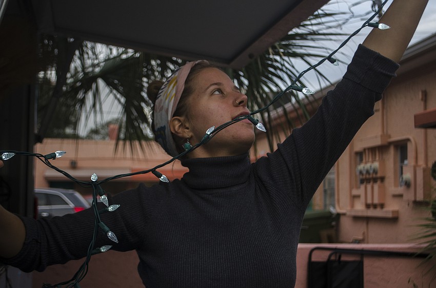 Madyson Williams hangs holiday lights on the Amish Bakery truck before the Burns Court Neighborhood Association Holiday Scavenger Hunt.
