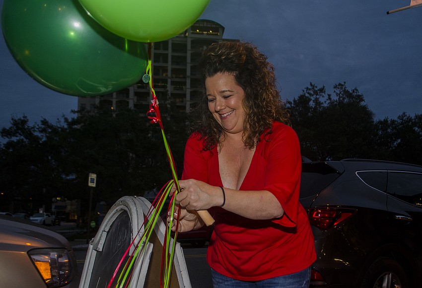 Owner of Pineapple Bay Trading Company Cari Staples ties balloons to a sign outside her store.