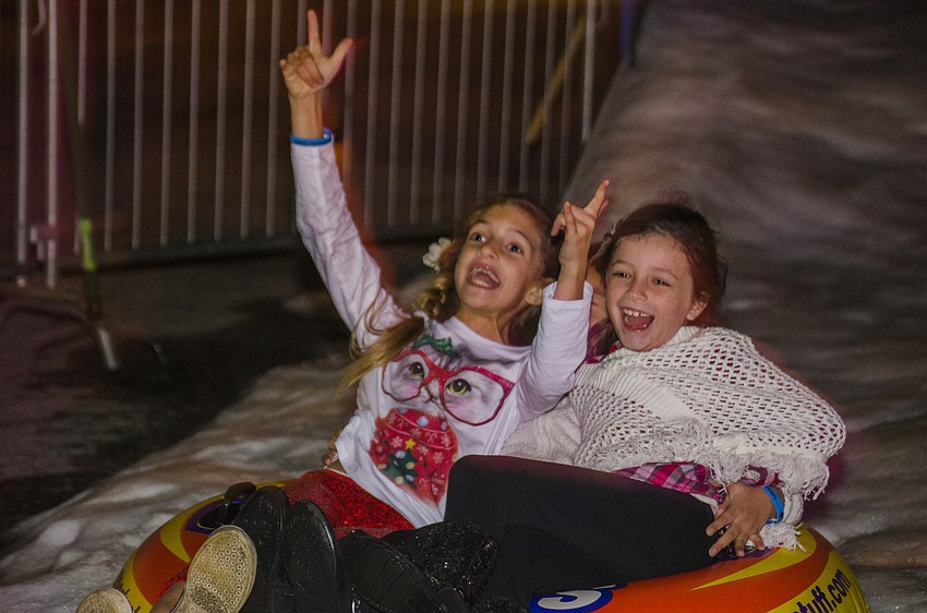 Isabella Savage and Madison Anderson sled down the snow slide.