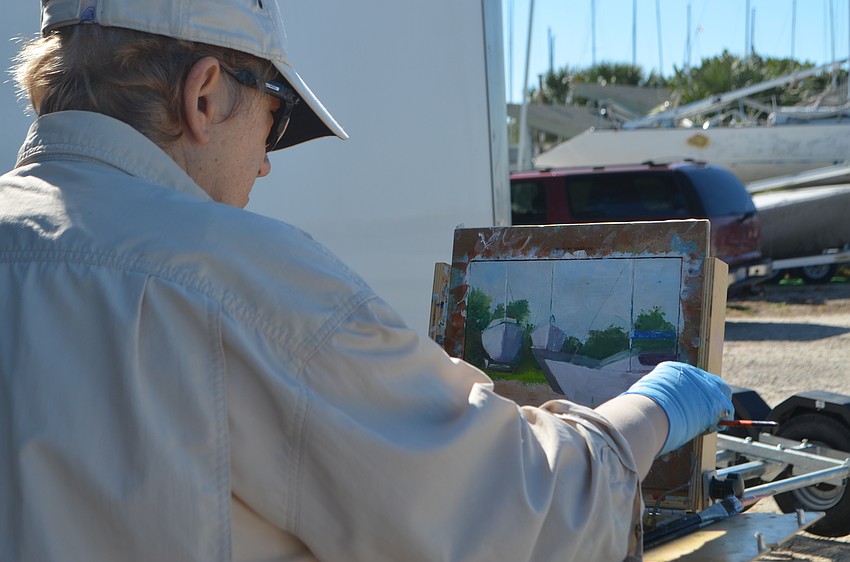 Katherine Reyes paints sailboats being stored at the Sarasota Sailing Squadron.