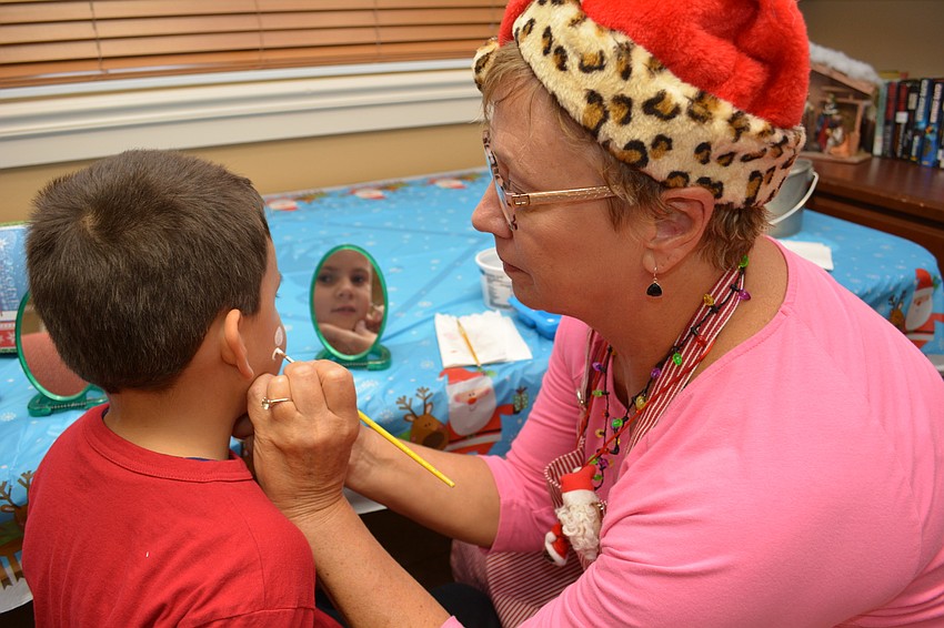 Andrew Fertig, 7, has his face painted by Cindi Gallant.