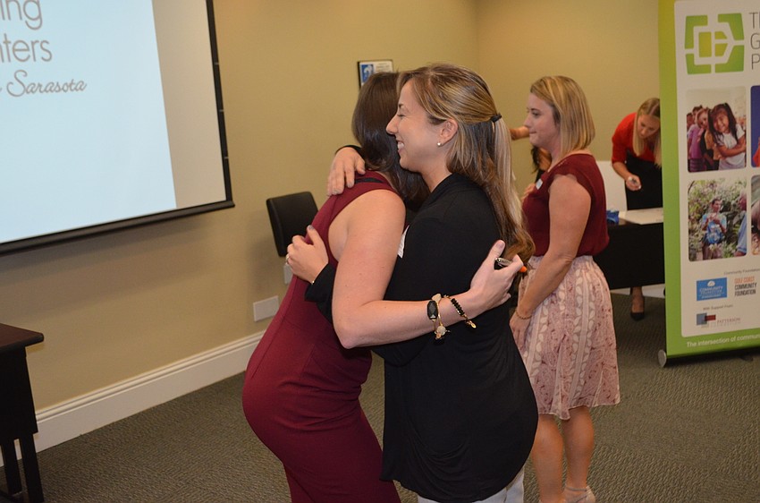 Jen Rust hugs Erin Kabinoff of Mote Marine before awarding her a grant check.