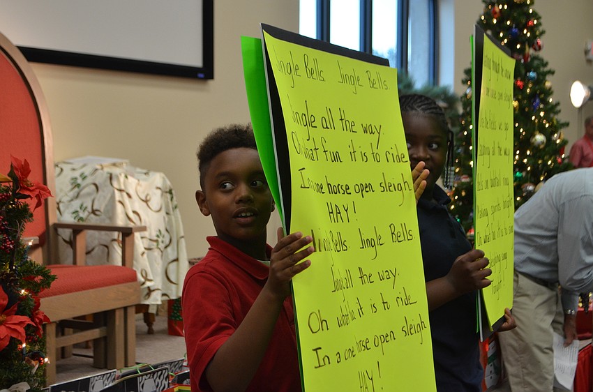 Students hold up signs with the lyrics to “Jingle Bells” during a short sing-a-long.