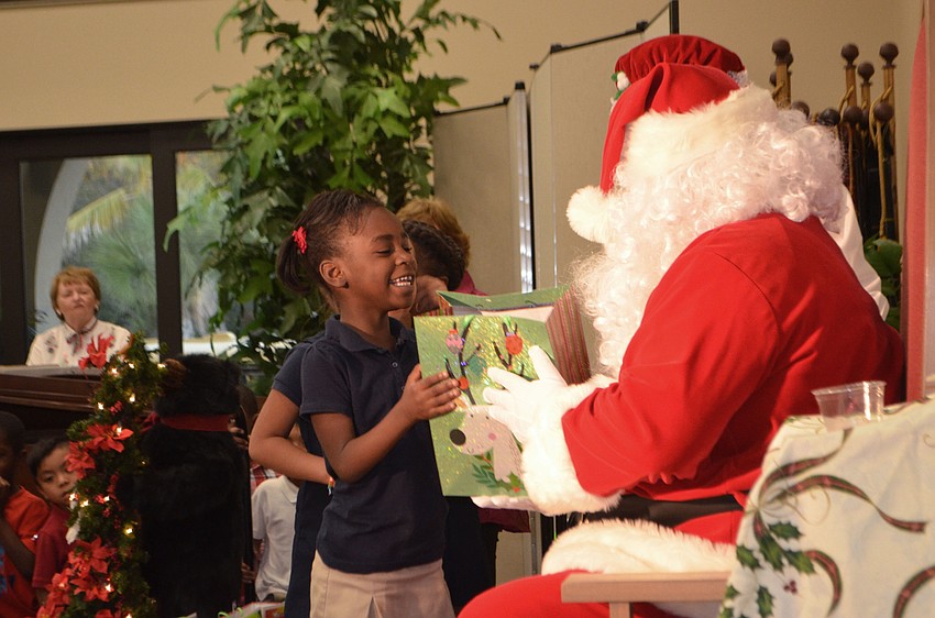 Trinity Houston smiles as she gets a gift from Santa Claus.