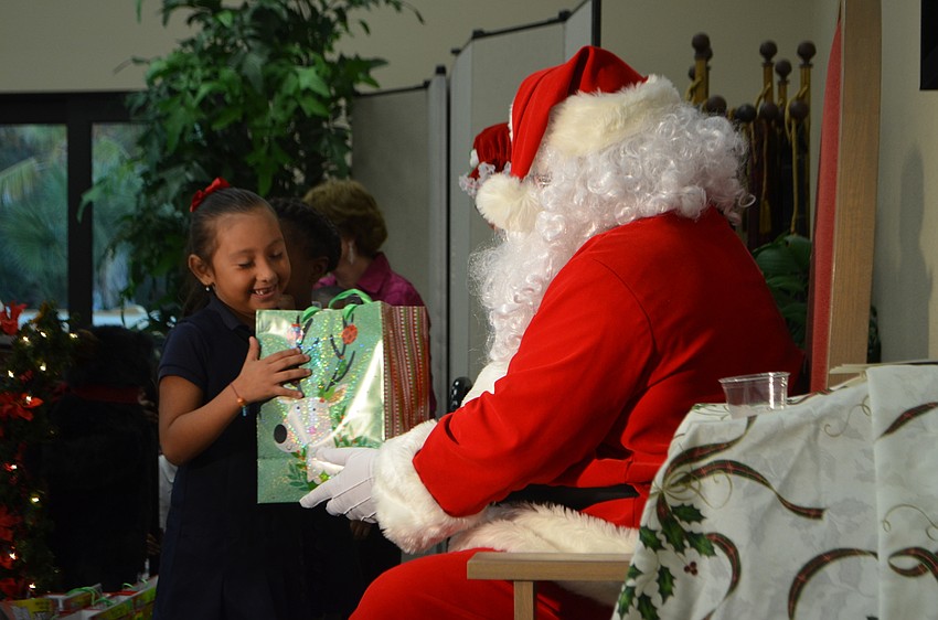 Santa Claus gives Briana Caranza a gift during Christ Church’s Reading Buddies holiday party.